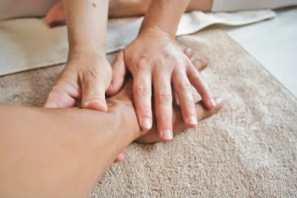 A person receiving a hand massage on a soft brown towel